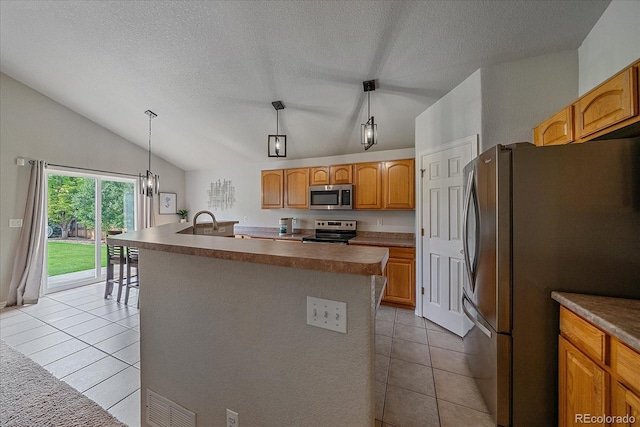 10723 W 54th Pl, Arvada, CO 80002 - kitchen with appliances with stainless steel finishes, vaulted ceiling, a kitchen island with sink, light tile patterned flooring, and a textured ceiling