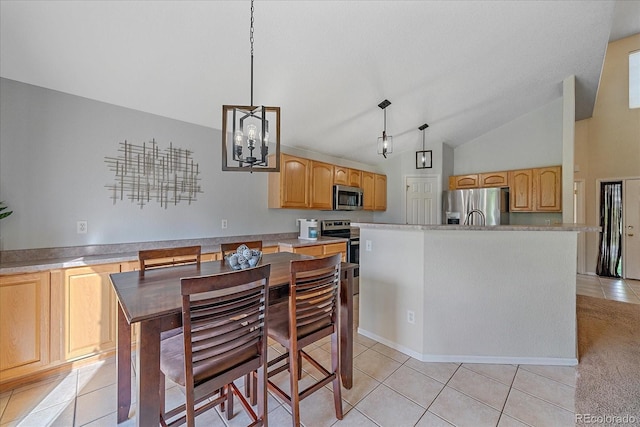 10723 W 54th Pl, Arvada, CO 80002 - kitchen with appliances with stainless steel finishes, light tile patterned floors, vaulted ceiling, a kitchen island with sink, and light brown cabinets