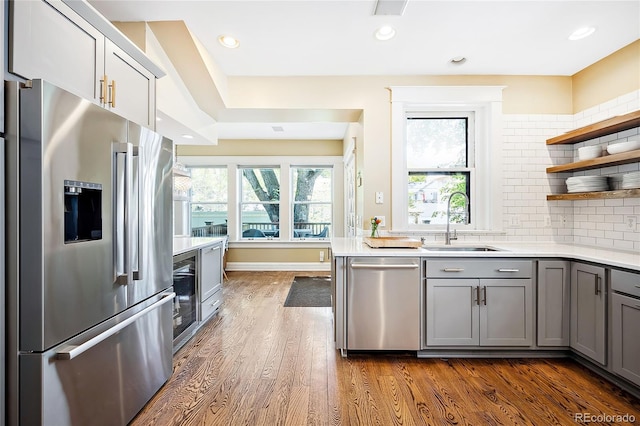 kitchen with gray cabinets, appliances with stainless steel finishes, dark hardwood / wood-style floors, sink, and decorative backsplash