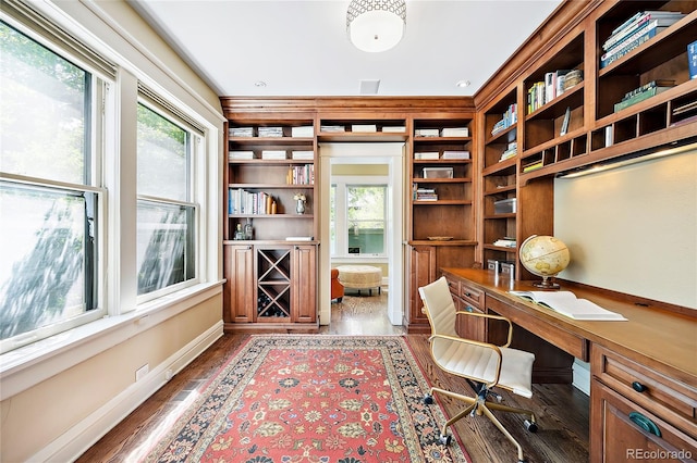 office with dark hardwood / wood-style floors and built in desk