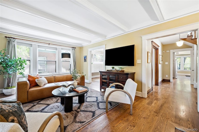 living room with beamed ceiling, crown molding, a healthy amount of sunlight, and light hardwood / wood-style floors