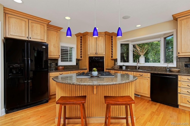 kitchen with tasteful backsplash, light hardwood / wood-style flooring, a kitchen bar, black appliances, and a center island