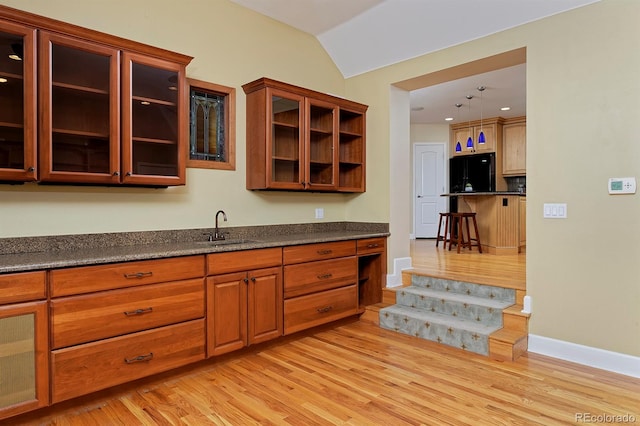 kitchen with dark stone countertops, light hardwood / wood-style flooring, black refrigerator, sink, and lofted ceiling