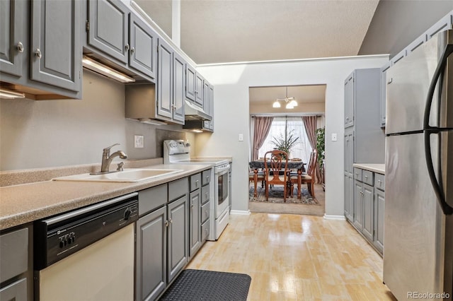 kitchen featuring light wood finished floors, white appliances, gray cabinetry, and a sink