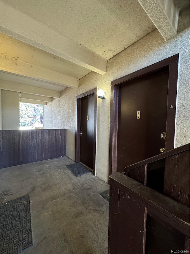 corridor featuring beam ceiling and a textured ceiling