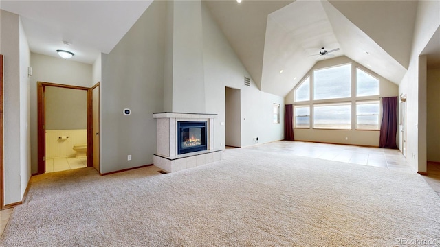 unfurnished living room with ceiling fan, a tile fireplace, light carpet, and high vaulted ceiling