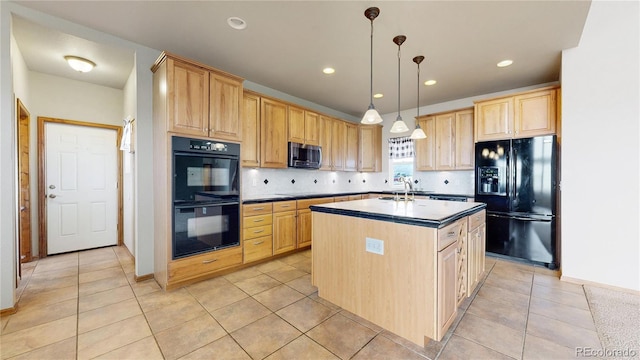 kitchen featuring black appliances, a center island with sink, light tile patterned floors, light brown cabinetry, and pendant lighting