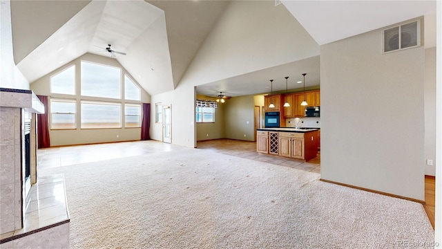 unfurnished living room featuring high vaulted ceiling, a wealth of natural light, light carpet, and ceiling fan