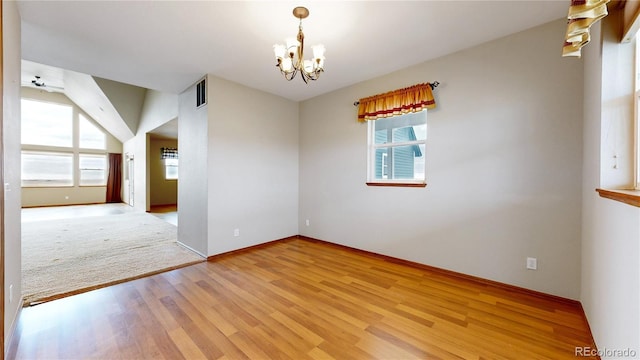 empty room with light hardwood / wood-style floors and ceiling fan with notable chandelier