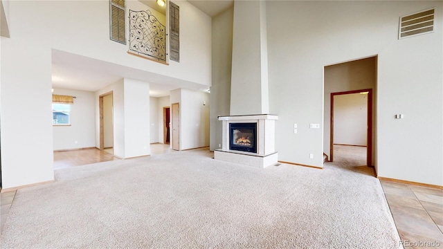 unfurnished living room featuring a high ceiling and light colored carpet