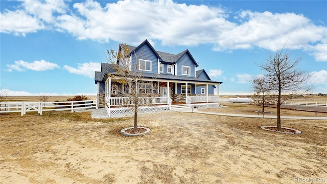 farmhouse-style home with covered porch and a rural view