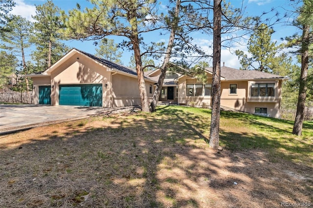 view of front of home with an attached garage, stucco siding, driveway, and a front yard