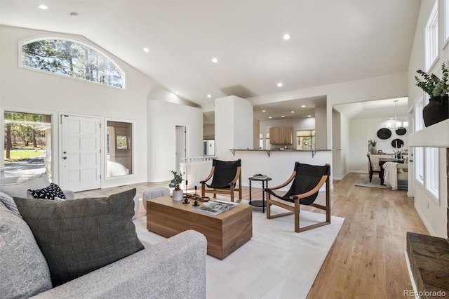 living room with high vaulted ceiling, light wood-style floors, and recessed lighting