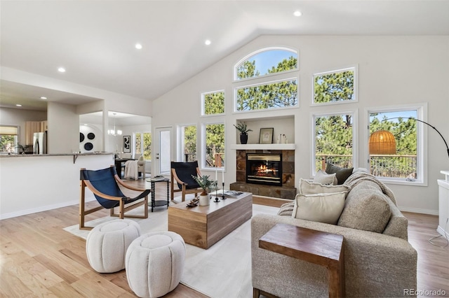 living area with healthy amount of natural light, a fireplace, light wood-type flooring, recessed lighting, and high vaulted ceiling