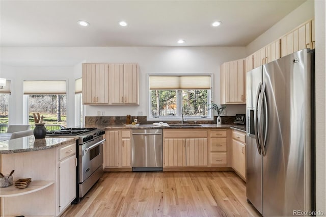 kitchen with appliances with stainless steel finishes, light brown cabinets, a sink, open shelves, and a peninsula