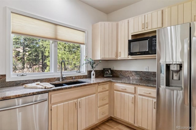 kitchen with stainless steel appliances, a sink, plenty of natural light, and dark stone counters