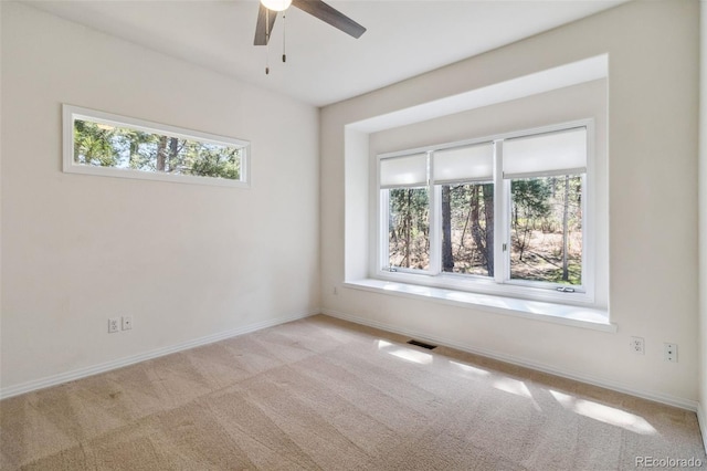 carpeted empty room featuring ceiling fan and baseboards