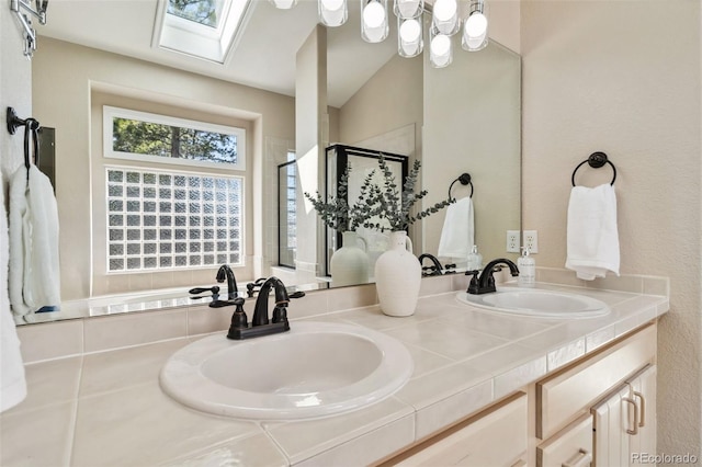 full bath featuring a stall shower, a skylight, and double vanity