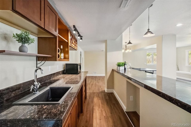 kitchen with a sink, open shelves, dark wood-style flooring, and brown cabinetry