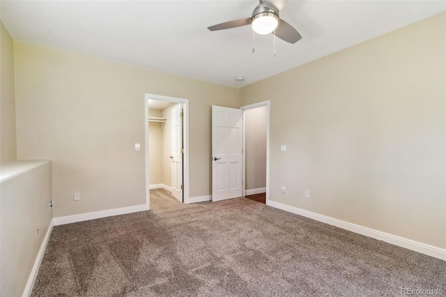 unfurnished bedroom featuring carpet floors, baseboards, a walk in closet, and a ceiling fan