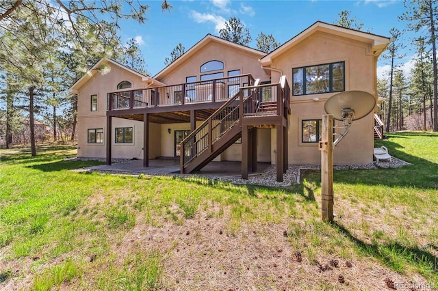 rear view of house with stairs, stucco siding, a deck, and a yard