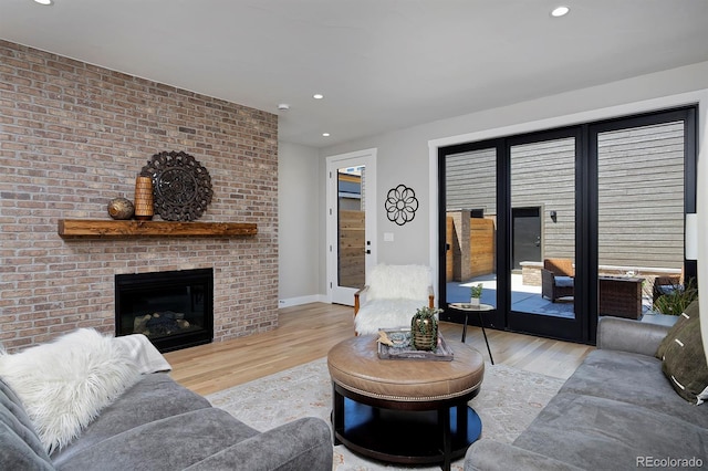 living room featuring a brick fireplace, brick wall, and light hardwood / wood-style floors