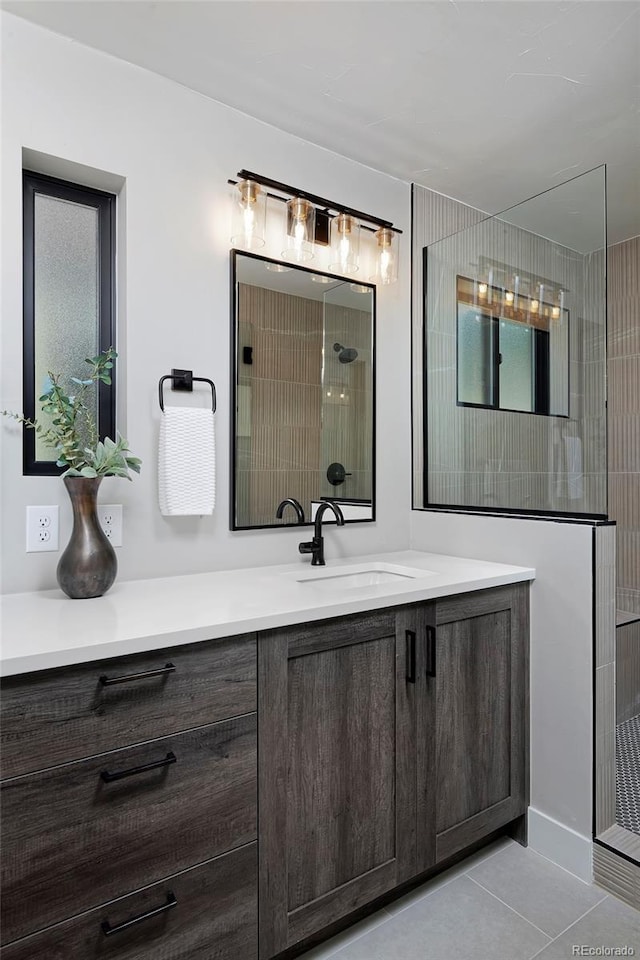 bathroom featuring a tile shower, vanity, and tile patterned floors