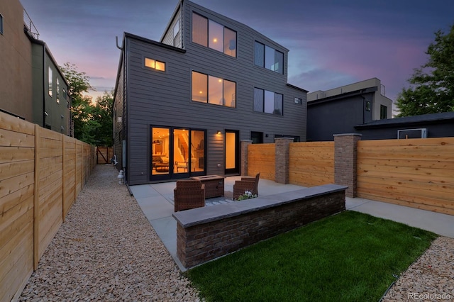 back house at dusk featuring outdoor lounge area and a patio area