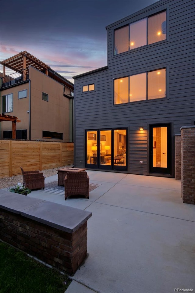 back house at dusk with an outdoor living space with a fire pit and a patio area