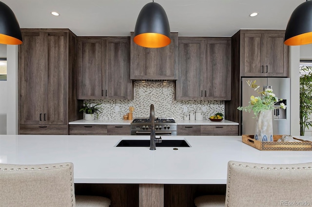 kitchen featuring appliances with stainless steel finishes, dark brown cabinetry, a breakfast bar area, and tasteful backsplash