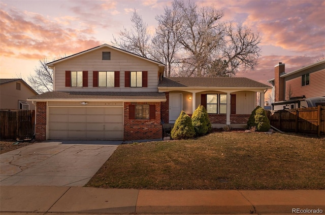 tri-level home with brick siding, an attached garage, concrete driveway, and fence