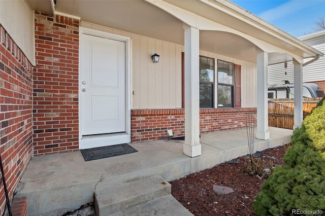 doorway to property featuring brick siding and covered porch