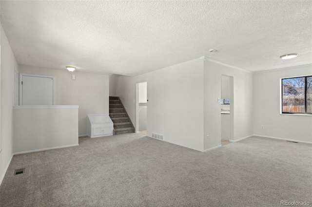 carpeted empty room featuring stairs, baseboards, and visible vents