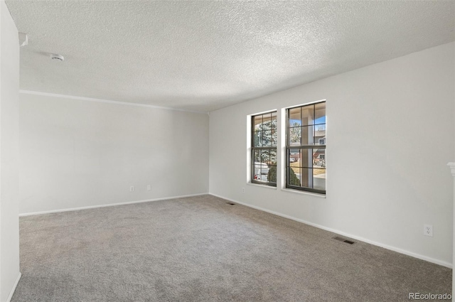 spare room featuring visible vents, carpet floors, a textured ceiling, and baseboards