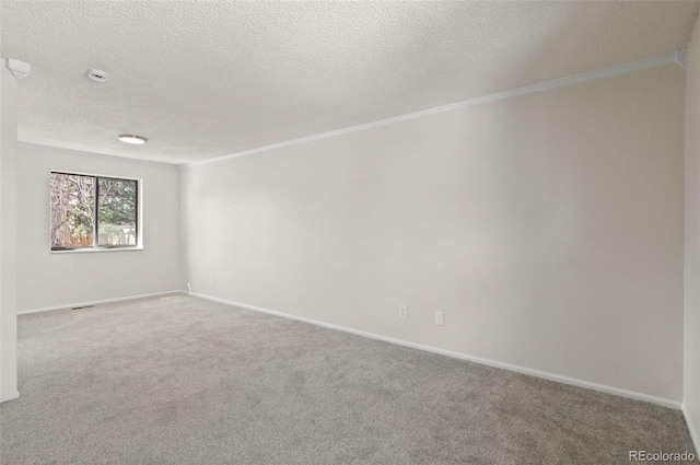 carpeted spare room with a textured ceiling, baseboards, and ornamental molding