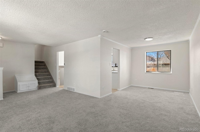 interior space featuring visible vents, baseboards, light colored carpet, stairs, and a textured ceiling