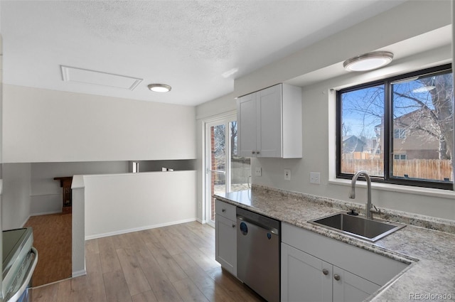 kitchen with a sink, stainless steel appliances, white cabinets, light wood-style floors, and a textured ceiling