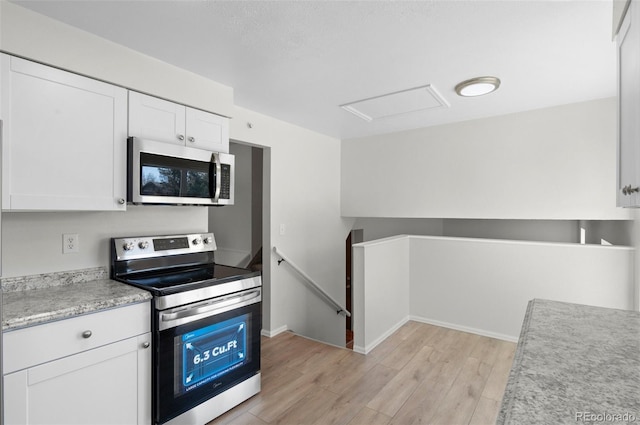 kitchen with white cabinetry, stainless steel appliances, light wood finished floors, baseboards, and light countertops