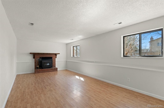 unfurnished living room with visible vents, baseboards, light wood-style floors, and a fireplace