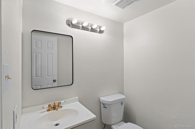 half bath with vanity, toilet, and visible vents