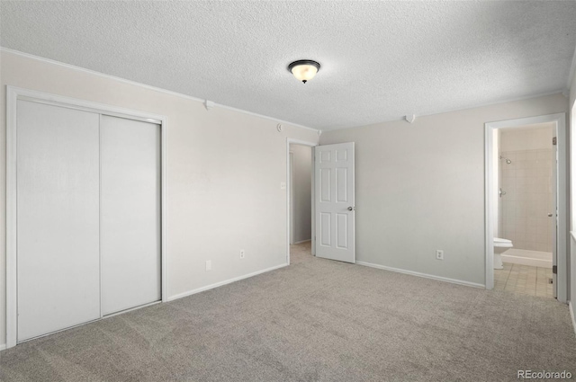 unfurnished bedroom with a closet, carpet, ensuite bath, and a textured ceiling