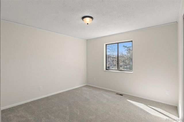 empty room featuring baseboards, visible vents, carpet floors, and a textured ceiling