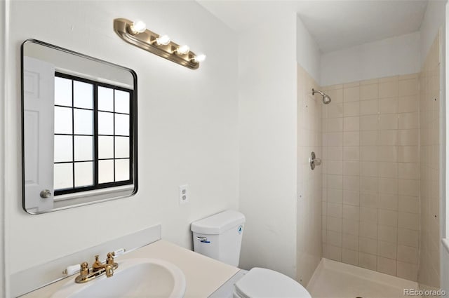 bathroom with toilet, vanity, and a tile shower