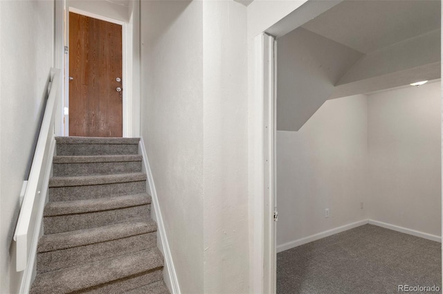 stairway featuring baseboards, lofted ceiling, and carpet flooring