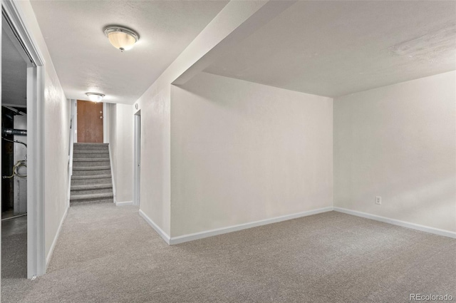 corridor with stairway, a textured ceiling, baseboards, and carpet