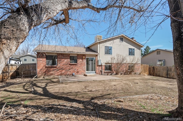 back of property with brick siding, a fenced backyard, a chimney, and a patio