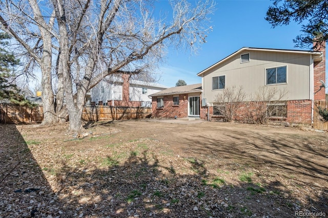 back of house with brick siding and fence