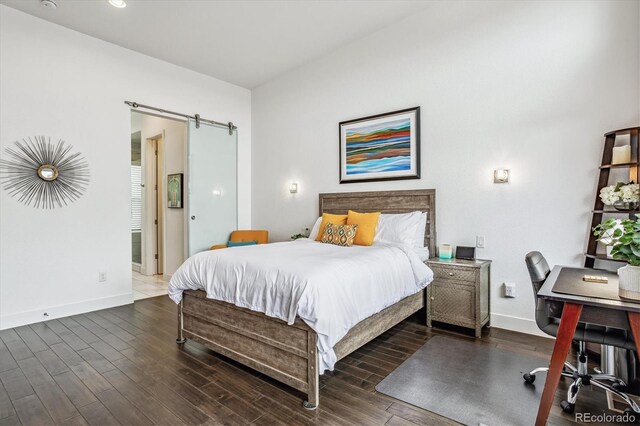 bedroom featuring a barn door and dark hardwood / wood-style floors