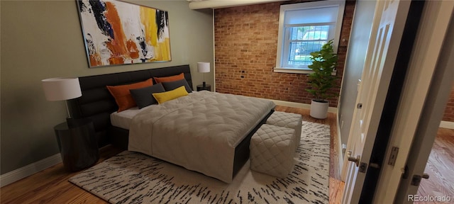 bedroom featuring hardwood / wood-style floors and brick wall