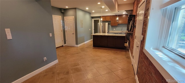 kitchen featuring sink, light tile patterned flooring, stainless steel refrigerator, and a kitchen island